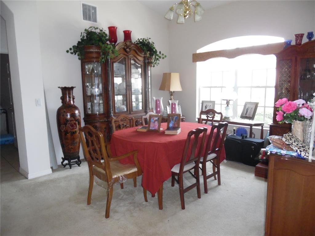 A dining room features a red-clothed table, wooden chairs, and a large china cabinet — 4841 GLEN COE STREET, LEESBURG, FL