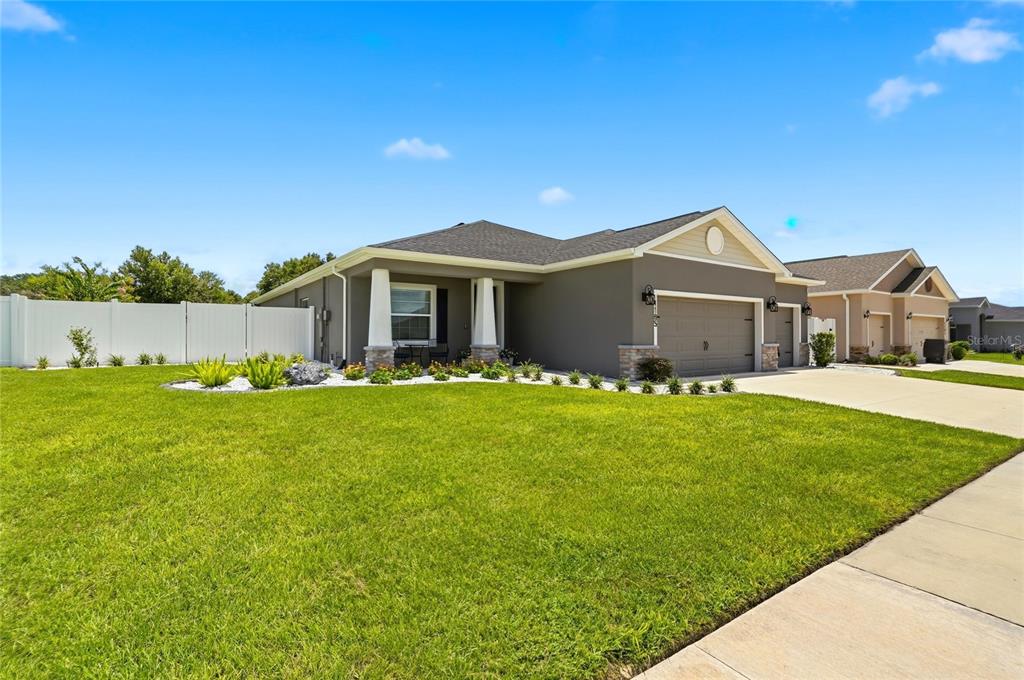 An open-concept living room features a brown leather sectional, hardwood floors, and an adjacent kitchen — 1185 SANDPIPER LOOP, WINTER HAVEN, FL