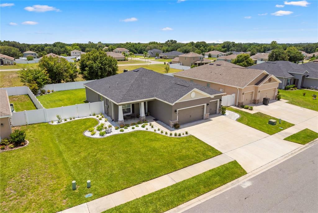 A modern kitchen features white cabinets, a large island with seating, and light wood flooring — 1185 SANDPIPER LOOP, WINTER HAVEN, FL
