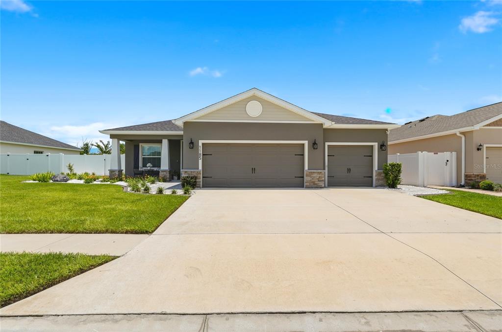 An aerial view shows a suburban house with a pool cage and a fenced backyard — 1185 SANDPIPER LOOP, WINTER HAVEN, FL