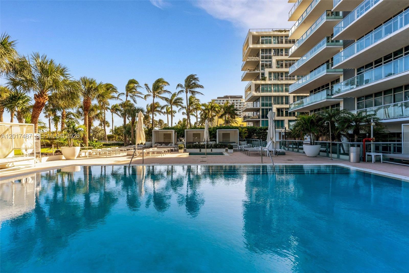 A swimming pool sits on a patio with lounge chairs, cabanas, and palm trees — 3737 Collins Ave # 403, Miami Beach FL 33140, MIAMI BEACH, FL