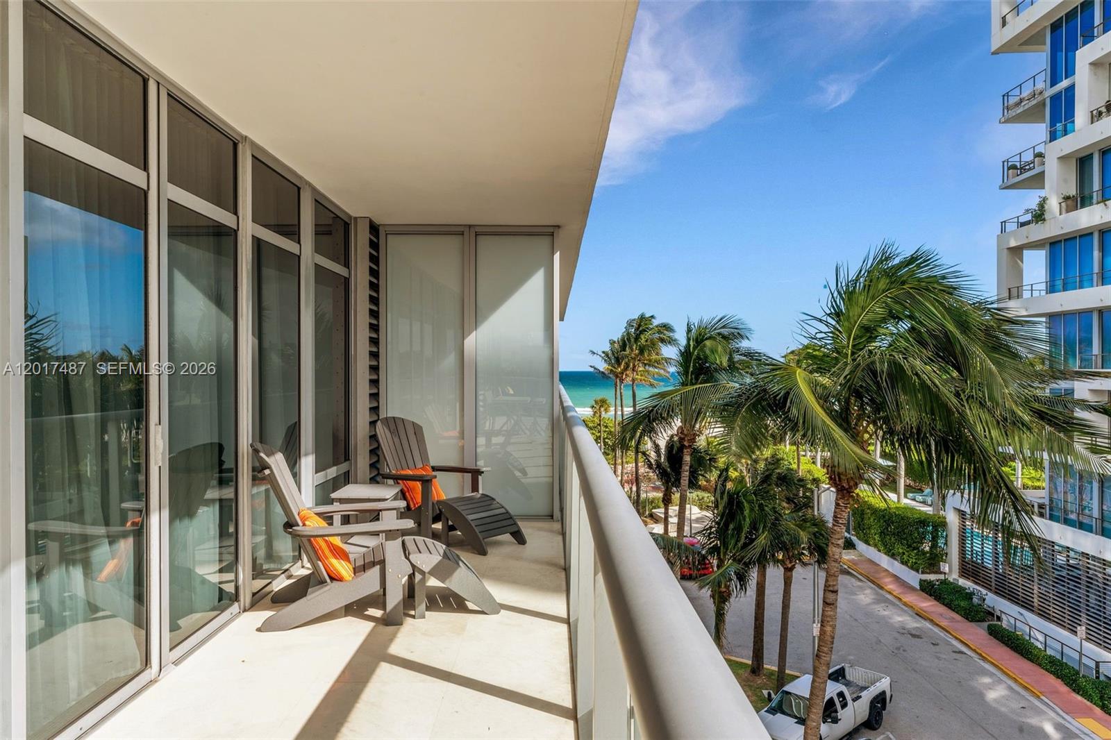 A balcony with two chairs overlooks a street, palm trees, and the ocean — 3737 Collins Ave # 403, Miami Beach FL 33140, MIAMI BEACH, FL