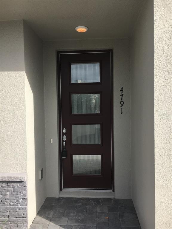 A dark brown front door with four glass panels is set in a stucco entryway — 4791 TERRA ESMERALDA DRIVE, KISSIMMEE, FL