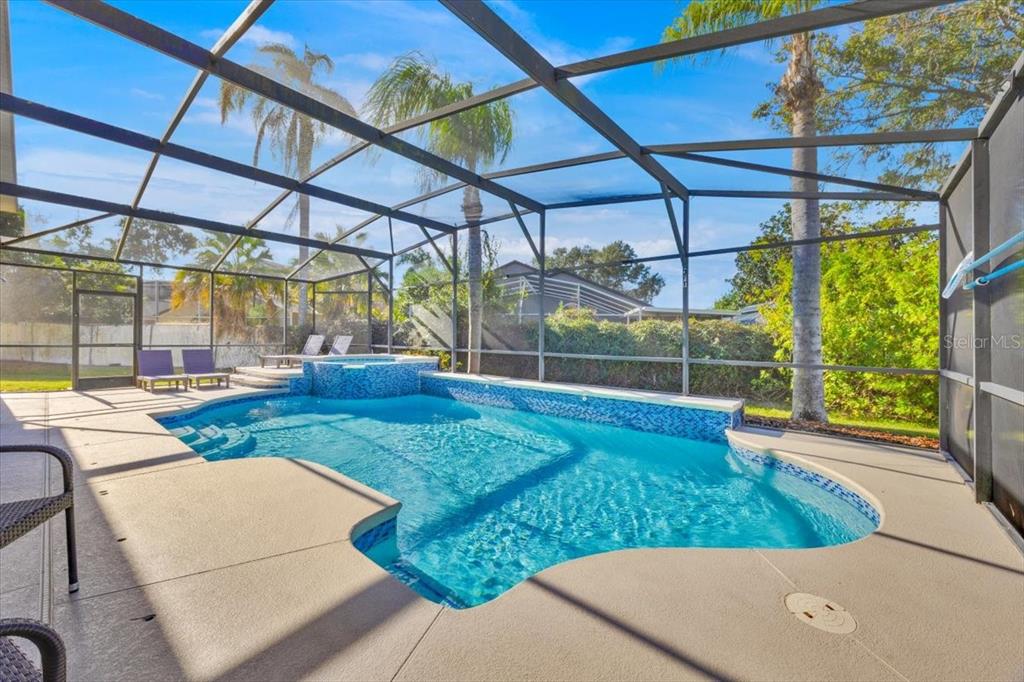 A swimming pool with a raised spa is enclosed by a screened lanai — 8023 ACADIA ESTATES COURT, KISSIMMEE, FL