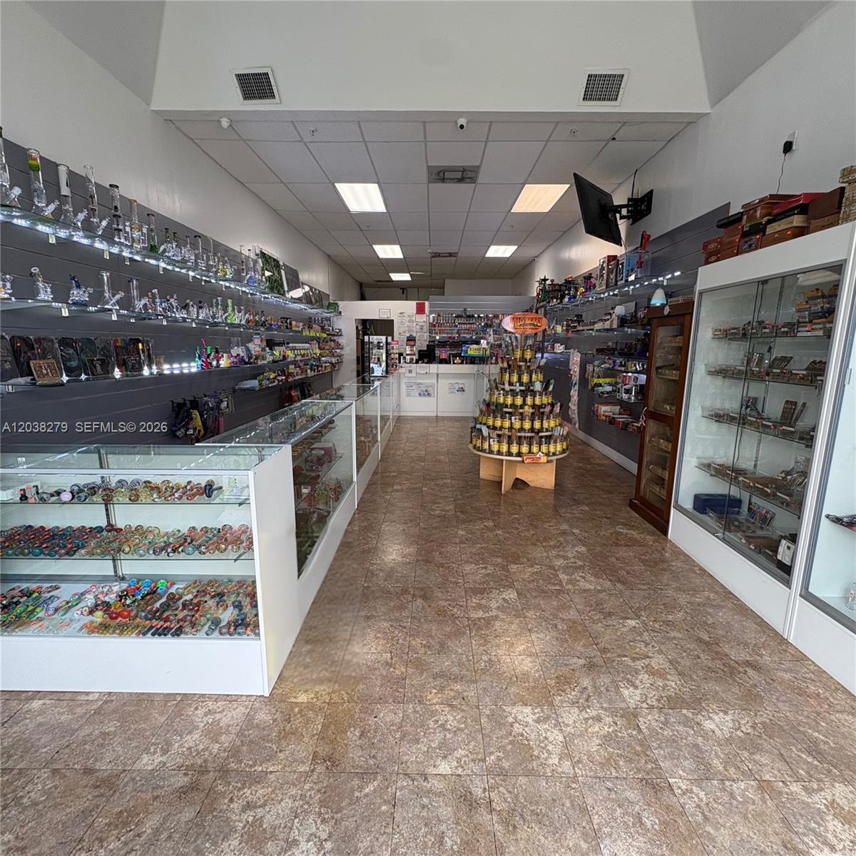 The interior of a retail smoke shop features glass display cases and wall-mounted shelving units — 5901 Johnson St, Hollywood FL 33021, HOLLYWOOD, FL