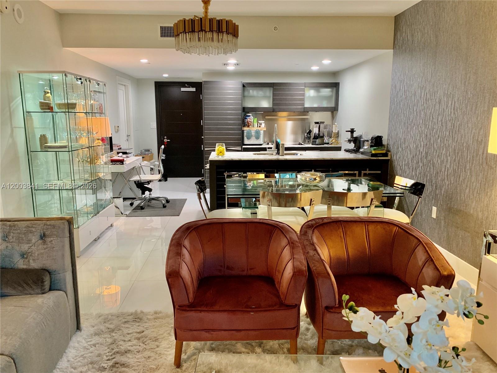 An open-concept living area features a kitchen, dining table, and two velvet armchairs — 200 Biscayne Boulevard Way # 4011, Miami FL 33131, MIAMI, FL