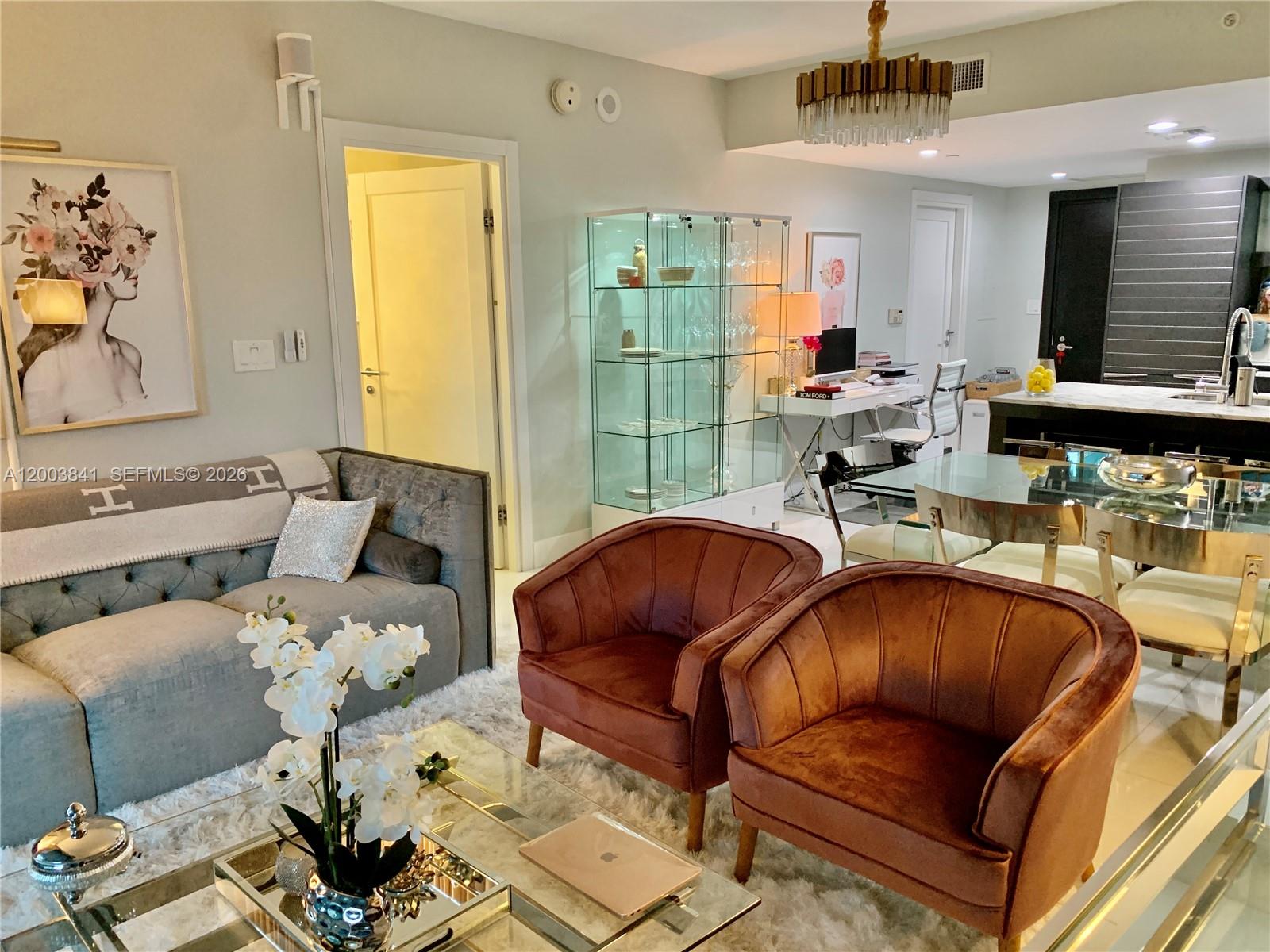 A living room features a grey sofa, two velvet armchairs, a glass display cabinet, and dining area — 200 Biscayne Boulevard Way # 4011, Miami FL 33131, MIAMI, FL