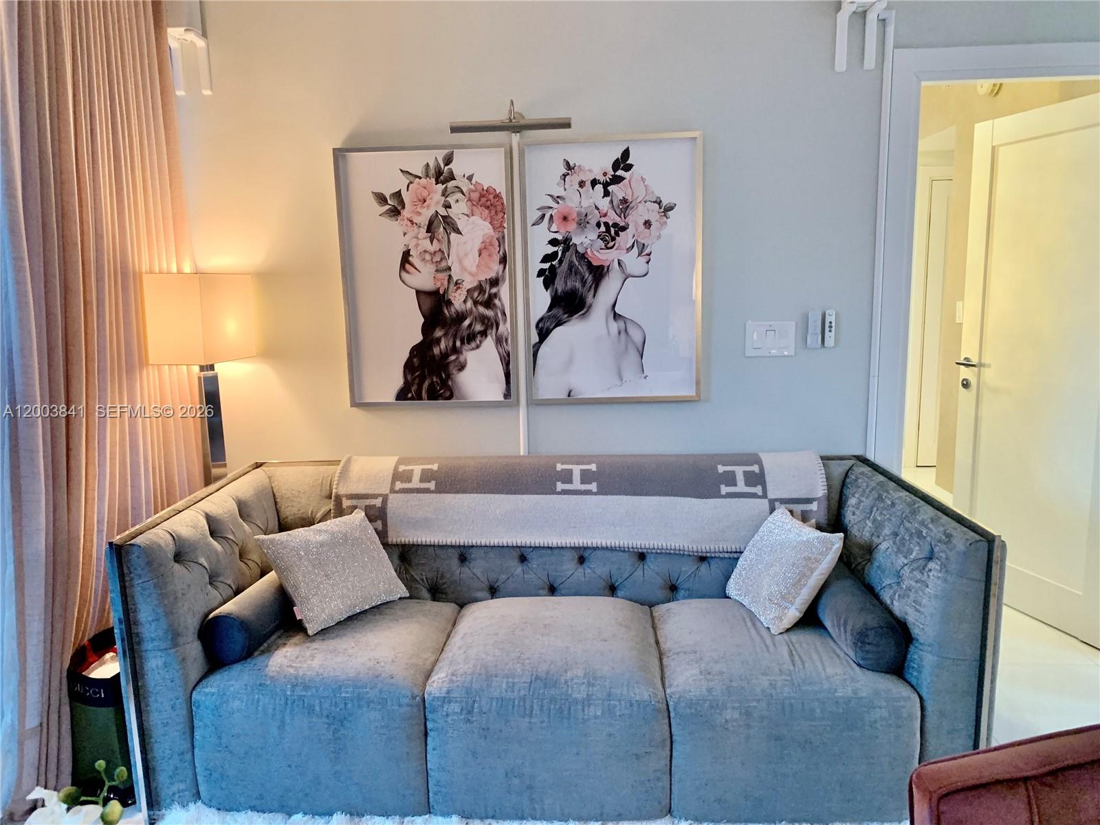 A gray tufted sofa sits beneath two floral portrait prints in a living room — 200 Biscayne Boulevard Way # 4011, Miami FL 33131, MIAMI, FL