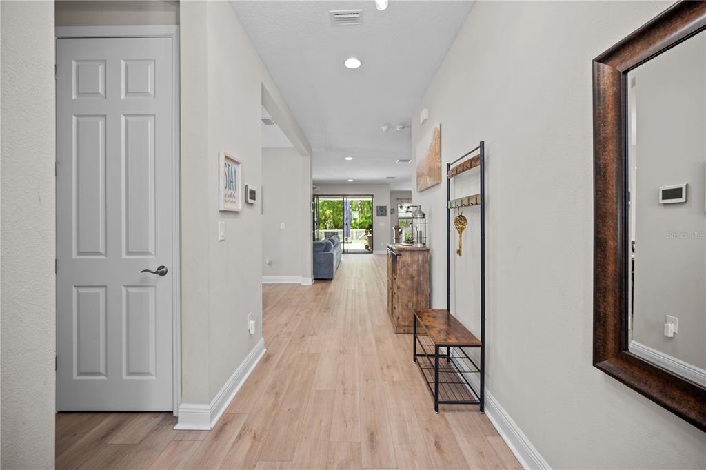A bright hallway with light wood-look flooring leads toward an open living area — 14734 HORSE TROT ROAD, LITHIA, FL