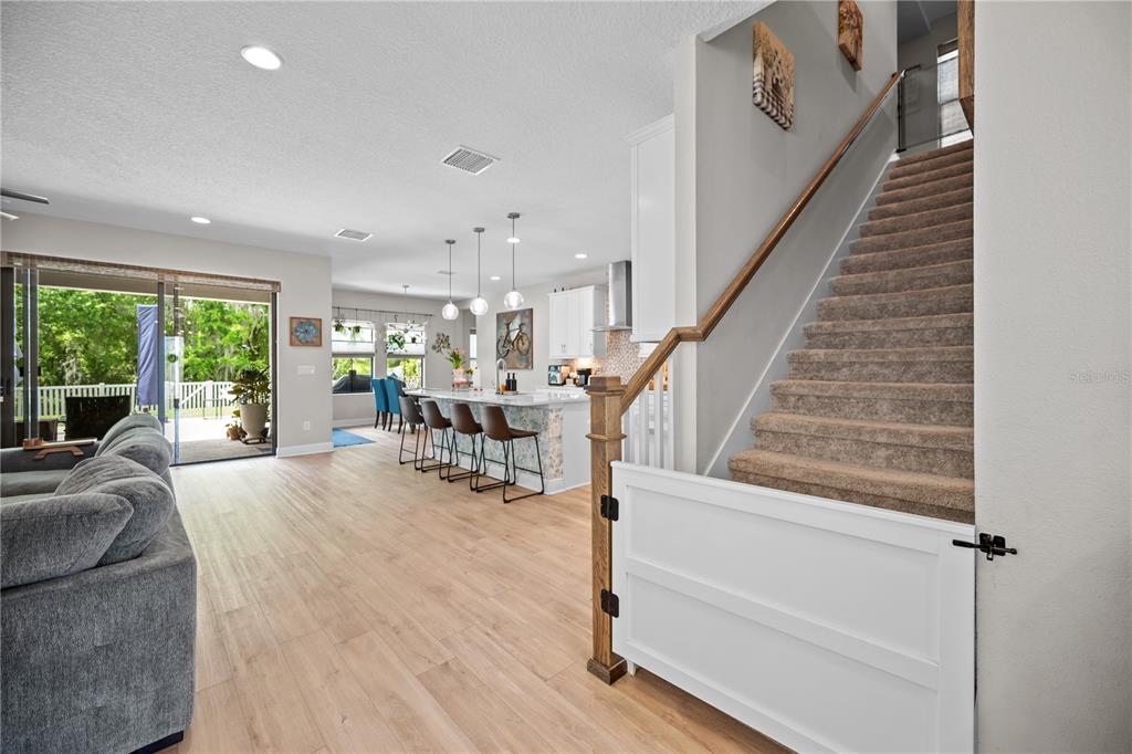 A living room and kitchen area with light wood flooring, a staircase, and sliding doors — 14734 HORSE TROT ROAD, LITHIA, FL