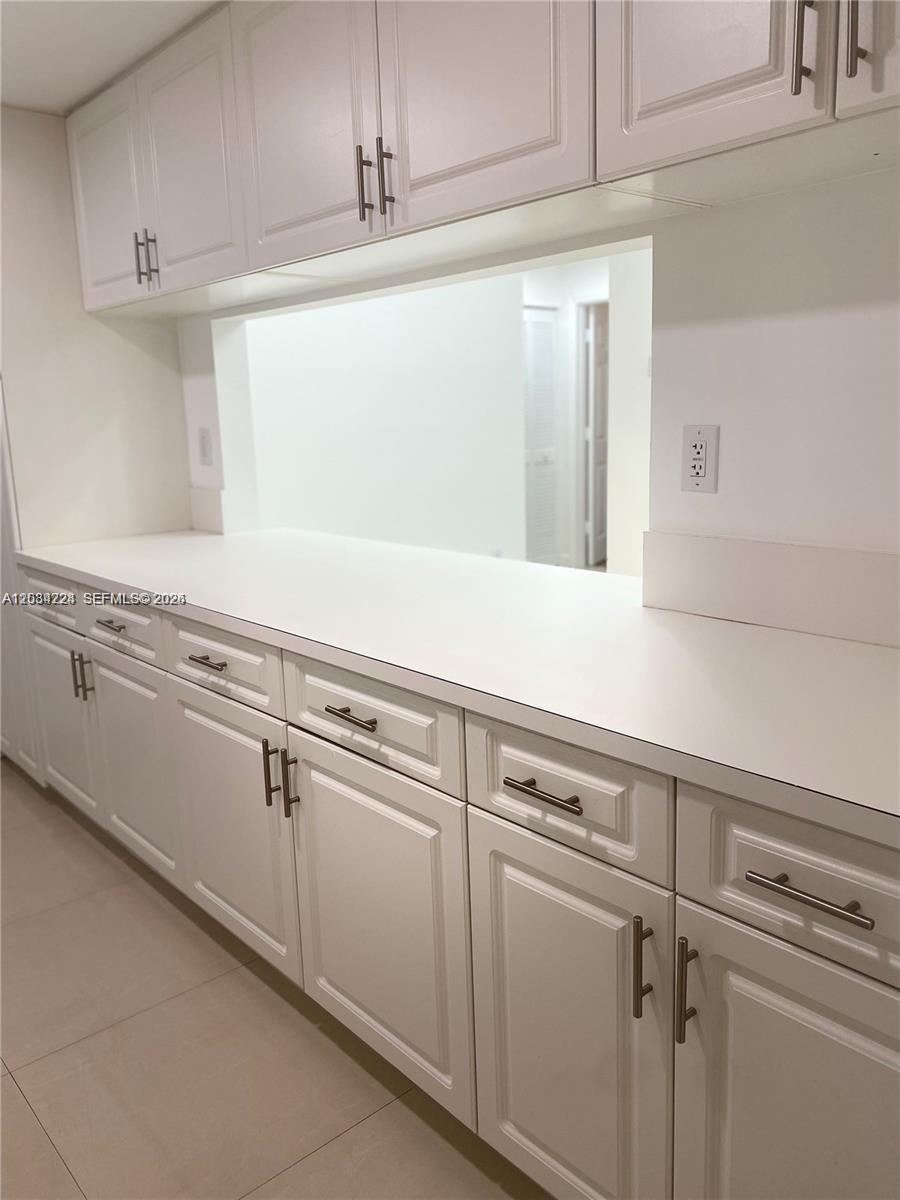 A kitchen features white cabinets, a white countertop, and a pass-through window to another room — 9805 NW 52nd St # 207, Doral FL 33178, DORAL, FL