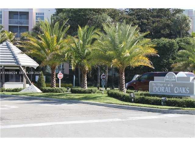 The entrance to The Village of Doral Oaks features palm trees and a community sign — 9805 NW 52nd St # 207, Doral FL 33178, DORAL, FL