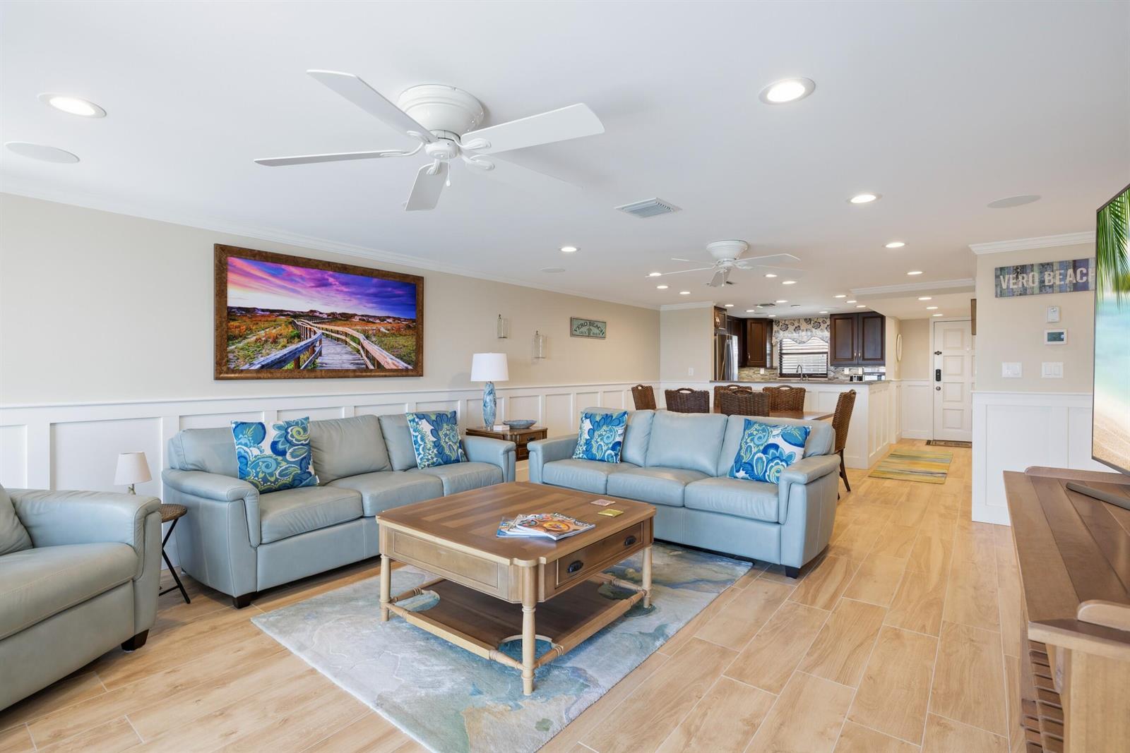 A living room features light blue sofas, a wooden coffee table, and wood-look tile flooring — INDIAN RIVER SHORES, FL