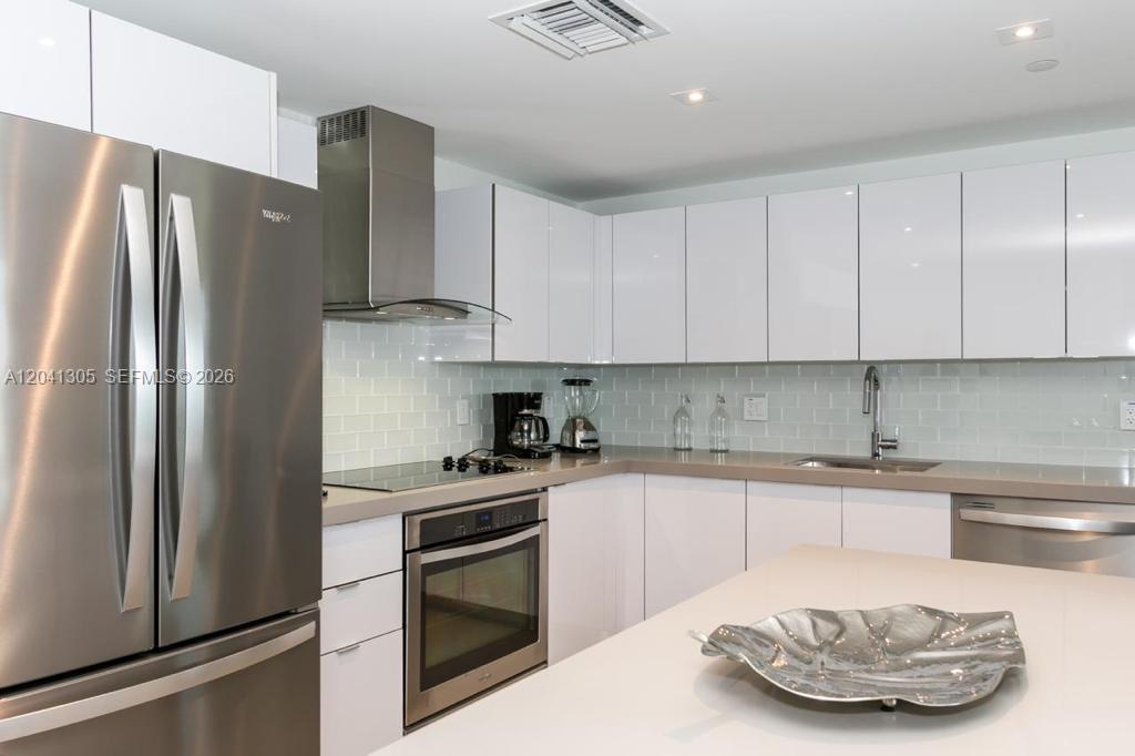 A modern kitchen features white cabinets, stainless steel appliances, and a light-colored countertop — MIAMI, FL