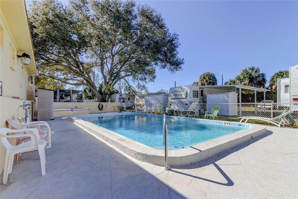 An outdoor swimming pool sits on a concrete patio next to a house and campers — 4776 66TH LANE N UNIT 12, ST PETERSBURG, FL