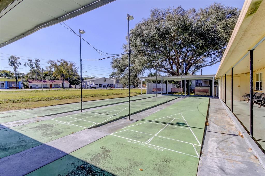 A covered outdoor shuffleboard court features multiple benches and a concrete patio area — 4776 66TH LANE N UNIT 12, ST PETERSBURG, FL