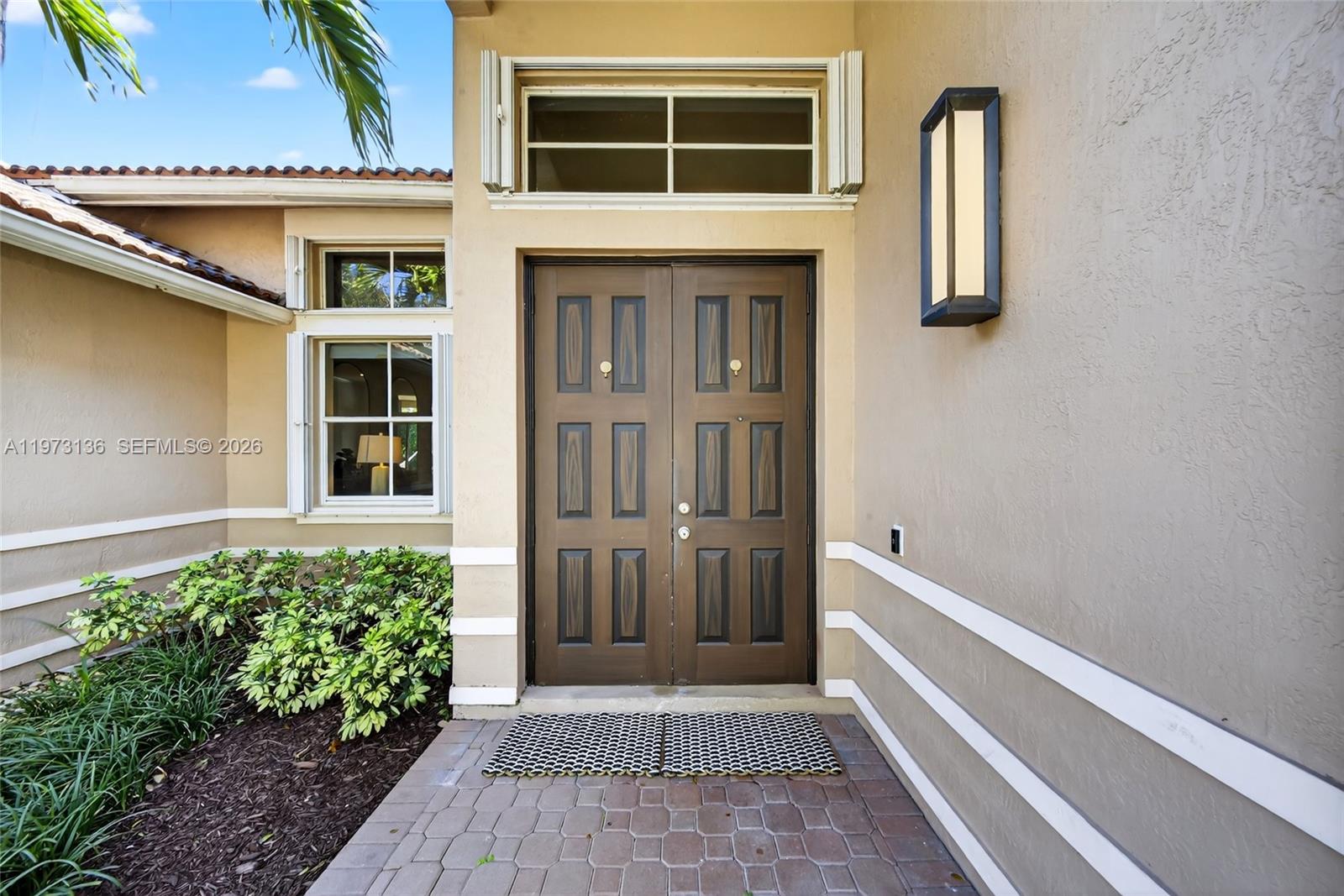 The exterior view shows a double front door with a transom window and wall sconce — 1623 Blue Jay Cir, Weston FL 33327, WESTON, FL