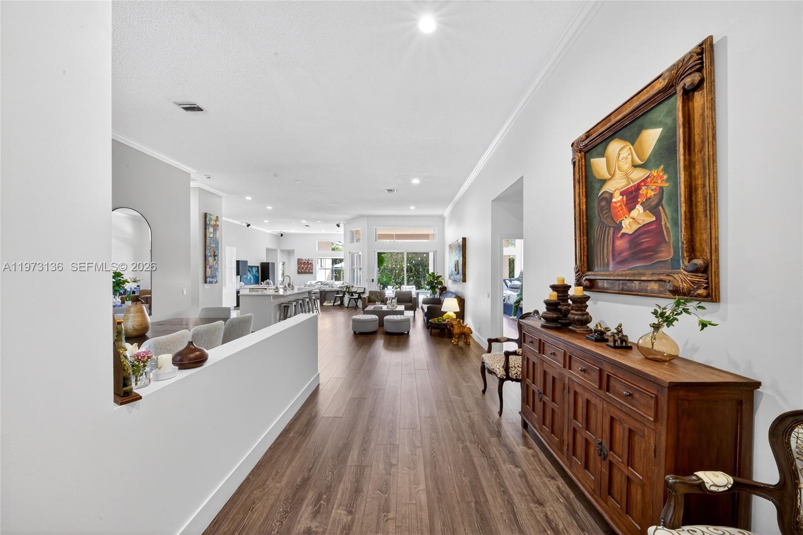 A spacious open-concept living area features wood-look flooring, a dining space, and a kitchen — 1623 Blue Jay Cir, Weston FL 33327, WESTON, FL