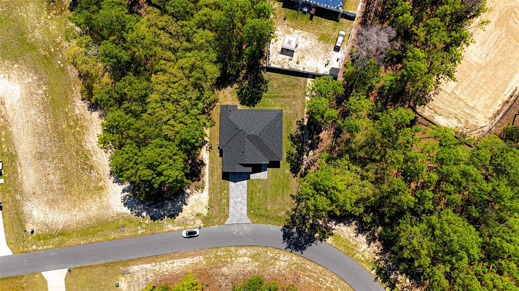 An aerial view shows a single-family house with a dark roof situated on a wooded lot — 15267 SW 50TH COURT ROAD, OCALA, FL