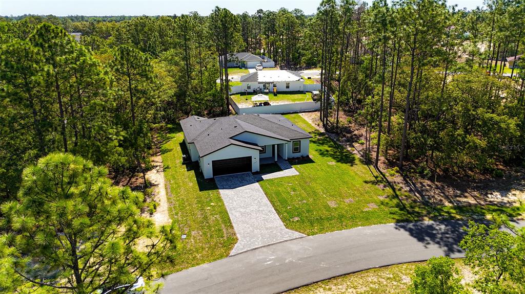 An aerial view shows a modern single-story house with a paved driveway and surrounding woods — 15267 SW 50TH COURT ROAD, OCALA, FL