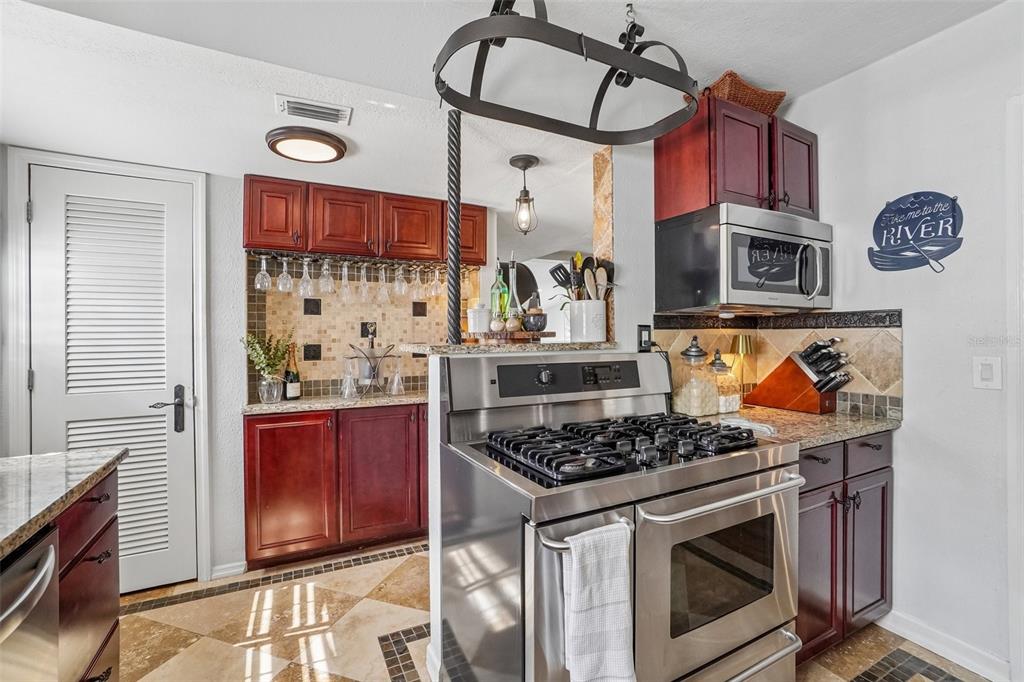 A kitchen features dark wood cabinets, stainless steel appliances, and a tiled backsplash — 1204 E PARK CIRCLE, TAMPA, FL