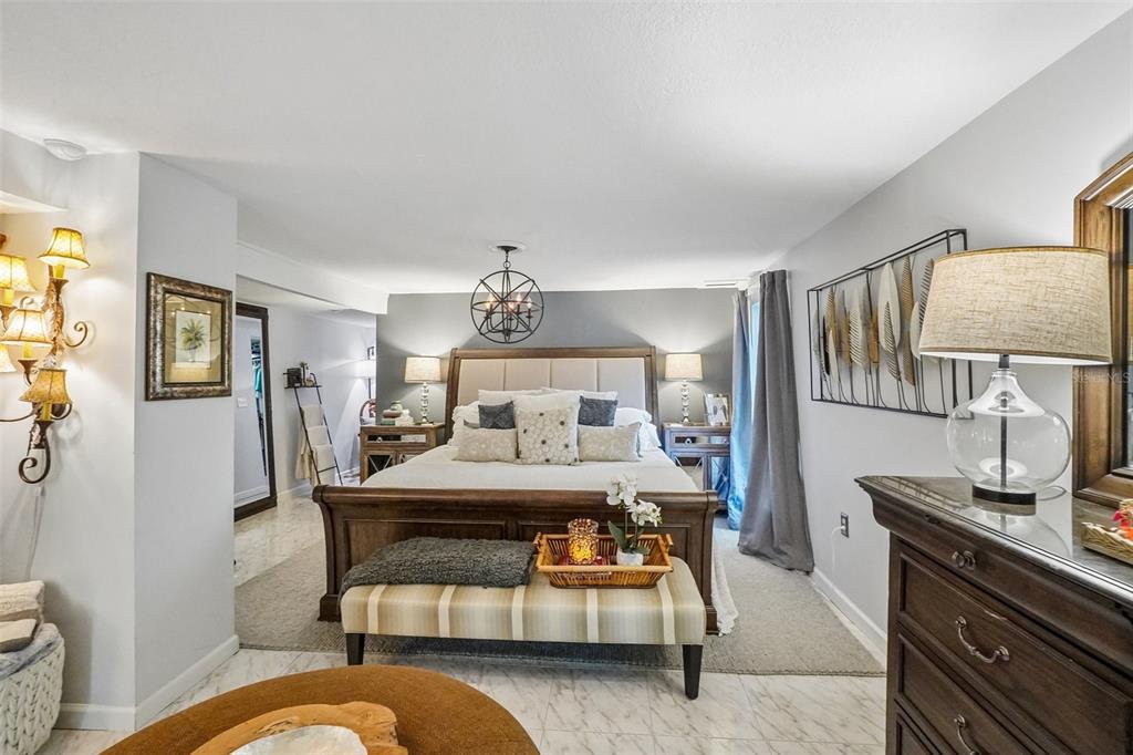 A bedroom features a wooden sleigh bed, a striped bench, and a modern chandelier — 1204 E PARK CIRCLE, TAMPA, FL