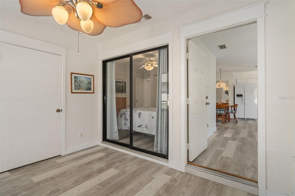 A room with light wood-look flooring, a sliding glass door, and an open doorway — 37810 ALISSA DRIVE, ZEPHYRHILLS, FL