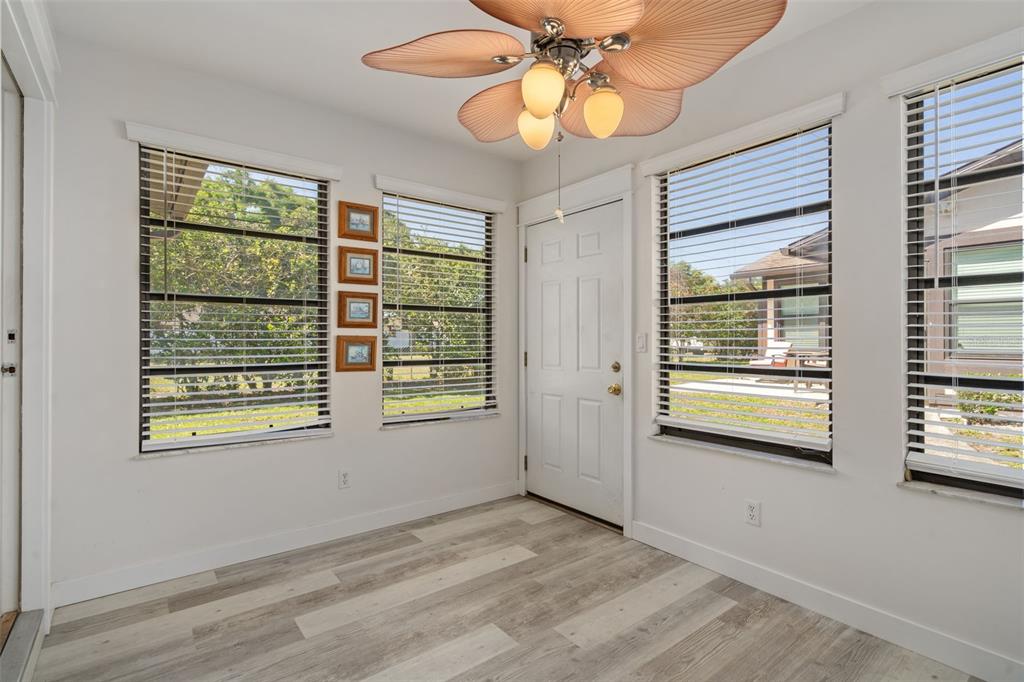 A sunroom with white walls, wood-look flooring, a palm-leaf ceiling fan, and several windows — 37810 ALISSA DRIVE, ZEPHYRHILLS, FL