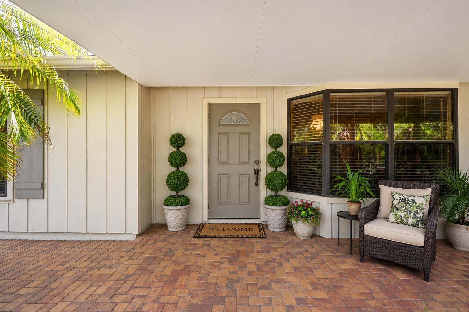 A front porch with a gray door, two topiary plants, and a wicker chair — 16208 132nd Terrace N, Jupiter FL 33478, JUPITER, FL