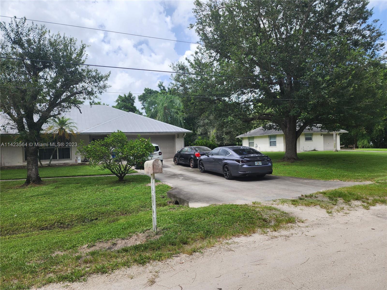 A gray house and a white house sit on a grassy lot with parked cars — 11845 N 171st Ln N, Jupiter FL 33478, JUPITER, FL