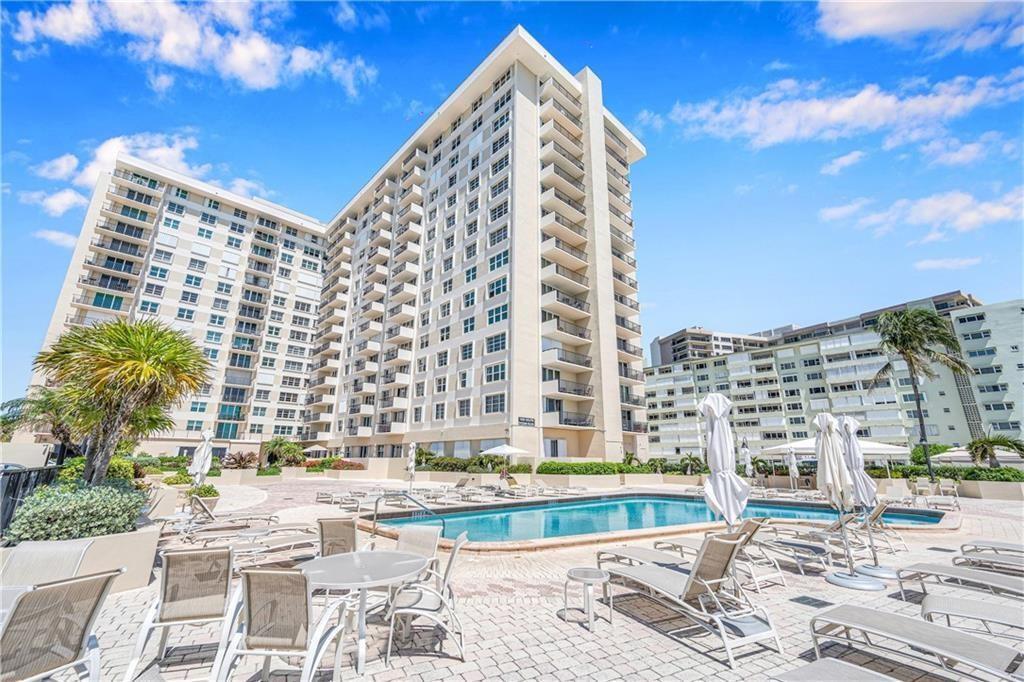 A swimming pool sits on a paved patio in front of a large residential building — 1900 S Ocean Boulevard Apt 6j, Pompano Beach FL 33062, POMPANO BEACH, FL