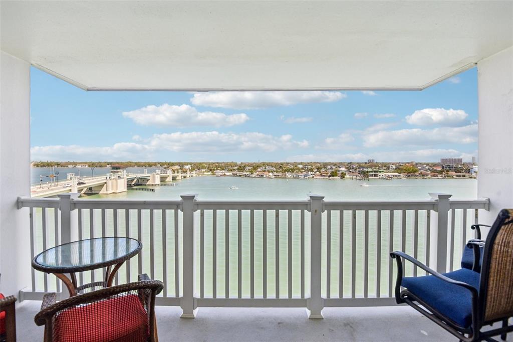 A balcony with patio furniture overlooks a body of water and a bridge — 500 TREASURE ISLAND CAUSEWAY UNIT 711, TREASURE ISLAND, FL