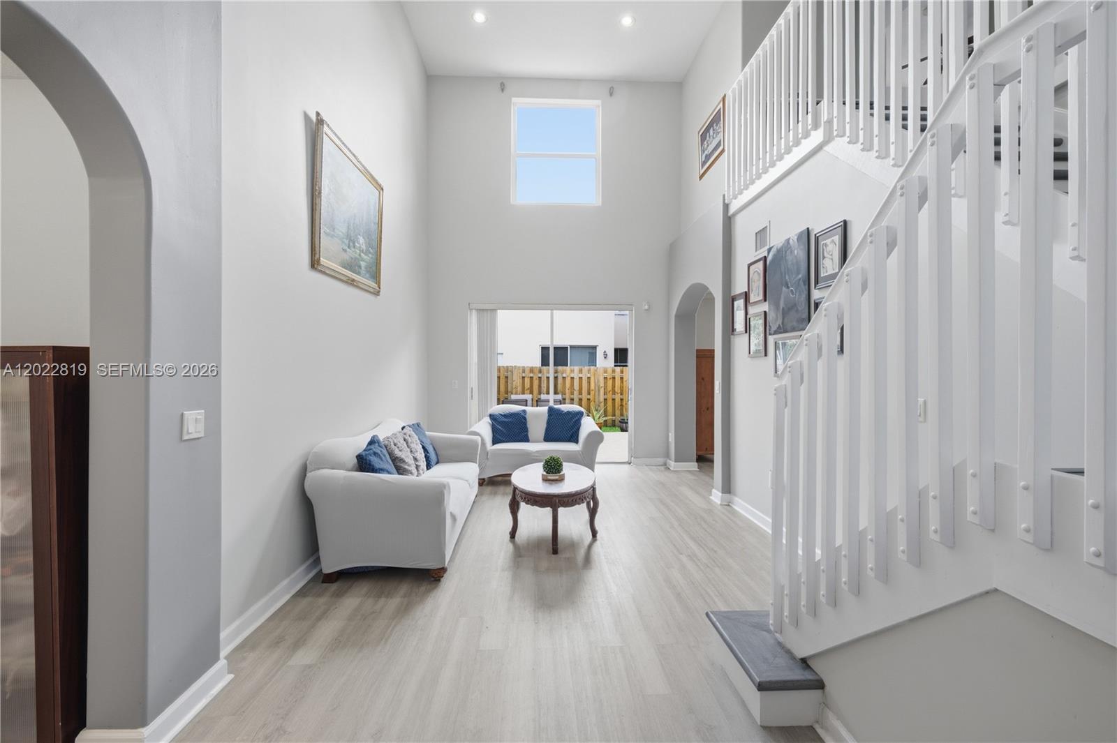 A living room with high ceilings, white walls, light wood floors, and a staircase — 16928 SW 35th St, Miramar FL 33027, MIRAMAR, FL