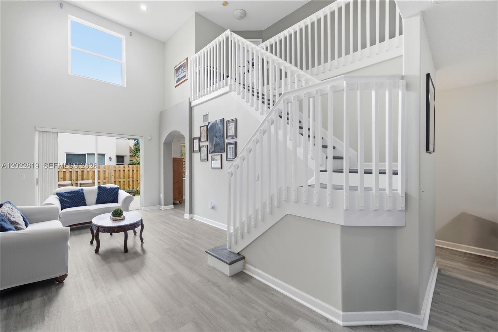 A living room features light wood flooring, a white staircase, and a high ceiling — 16928 SW 35th St, Miramar FL 33027, MIRAMAR, FL