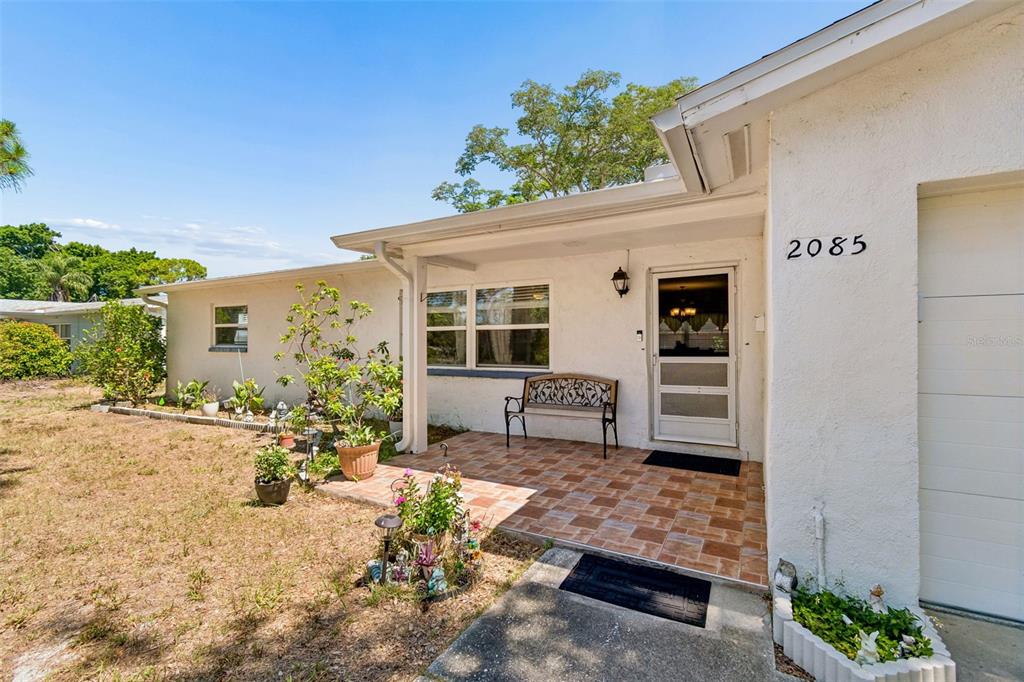 A white house exterior features a tiled front porch, a bench, and a garage door — 2085 68TH AVENUE S, ST PETERSBURG, FL