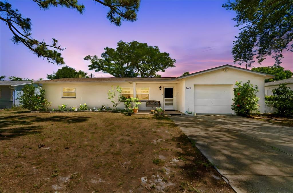A single-story house with a white exterior, a garage, and a front yard at dusk — 2085 68TH AVENUE S, ST PETERSBURG, FL