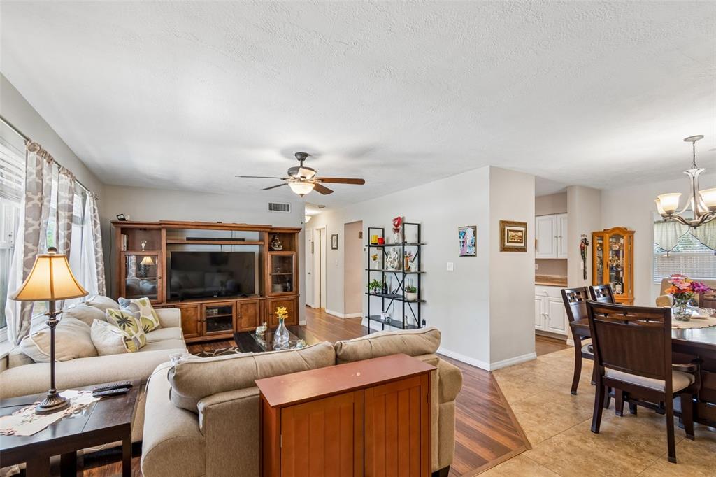 A living room with a sectional sofa, wooden entertainment center, and an adjacent dining area — 2085 68TH AVENUE S, ST PETERSBURG, FL