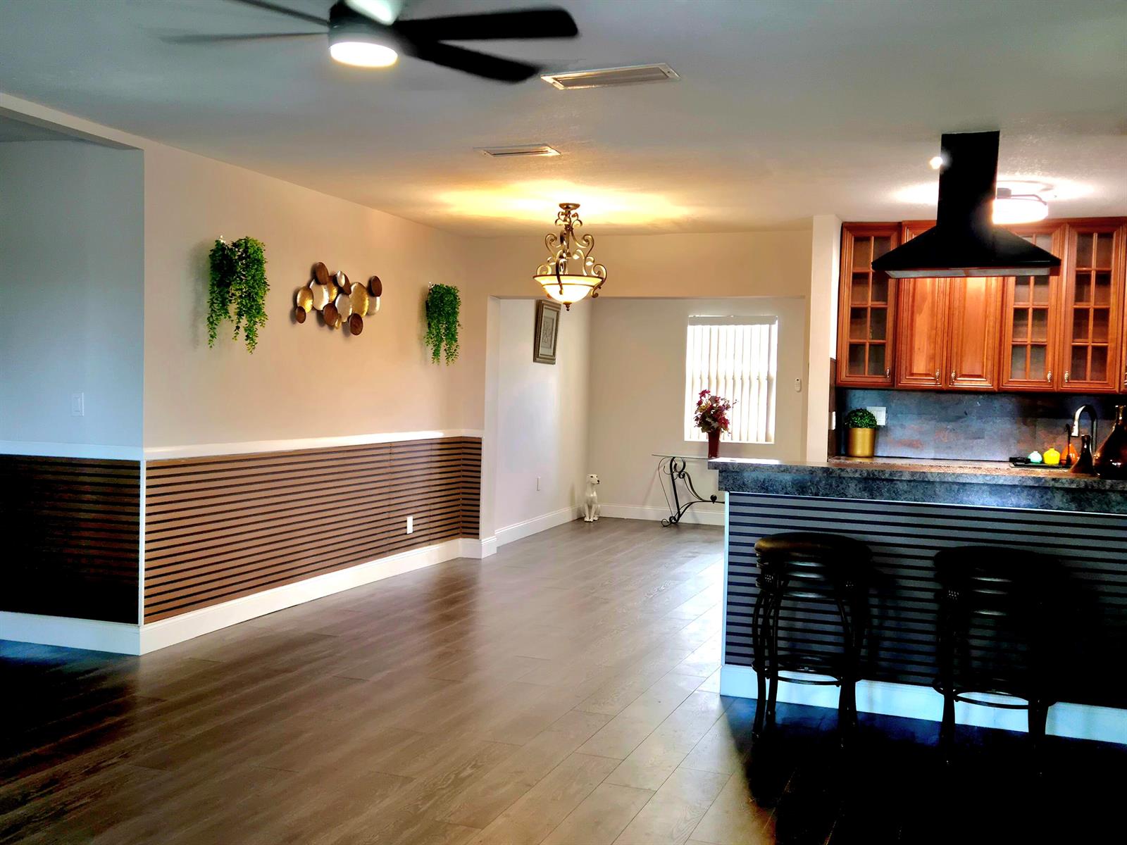 A kitchen with wood cabinets and a breakfast bar opens into a dining area — 1015 NW 68th Avenue, Margate FL 33063, MARGATE, FL