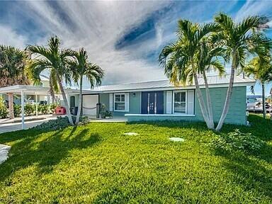 A single-story teal house with a metal roof and palm trees in the front yard — 2891 Cussell Drive, FL 33956, FL