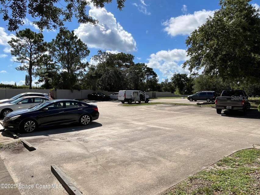 A paved parking lot features several parked vehicles under a bright, partly cloudy sky — 2755 BARNA AVENUE, TITUSVILLE, FL