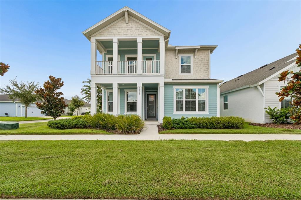 A two-story house features light blue siding, a covered front porch, and a second-story balcony — 28692 COZY CREEK DRIVE, WESLEY CHAPEL, FL