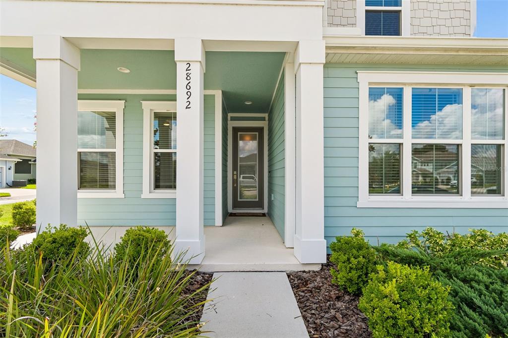 The exterior of a light blue house features a covered porch and a front door — 28692 COZY CREEK DRIVE, WESLEY CHAPEL, FL