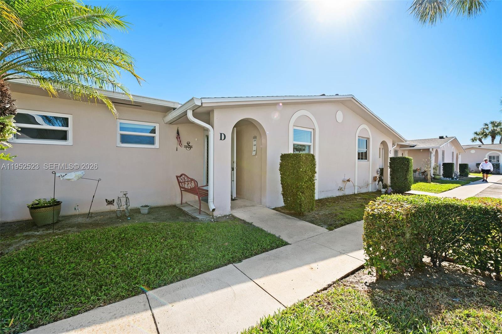 A single-story beige residential building features a walkway leading to a unit marked D — 2772 Dudley Dr E # D, West Palm Beach FL 33415, WEST PALM BEACH, FL