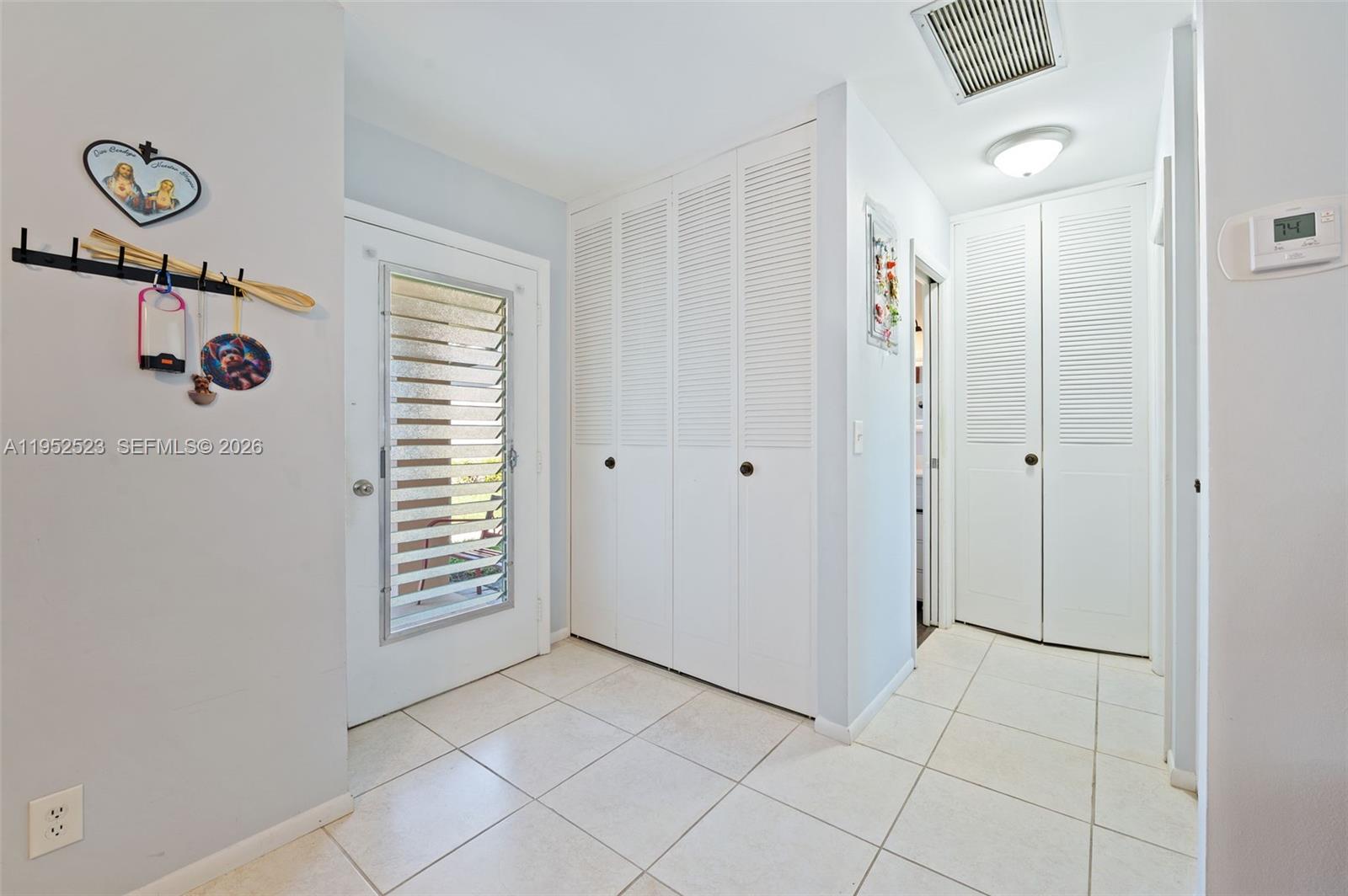 An entryway features white louvered closet doors, tiled flooring, and a door with blinds — 2772 Dudley Dr E # D, West Palm Beach FL 33415, WEST PALM BEACH, FL
