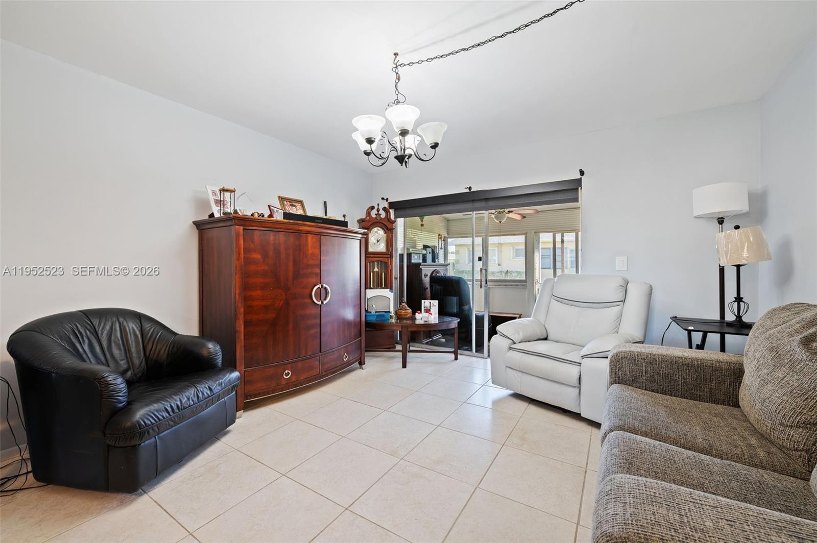 A living room features tile flooring, a large wooden armoire, and several pieces of furniture — 2772 Dudley Dr E # D, West Palm Beach FL 33415, WEST PALM BEACH, FL