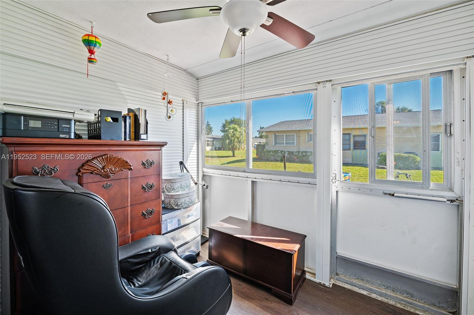 A sunroom features white paneled walls, a ceiling fan, a dresser, and a black chair — 2772 Dudley Dr E # D, West Palm Beach FL 33415, WEST PALM BEACH, FL