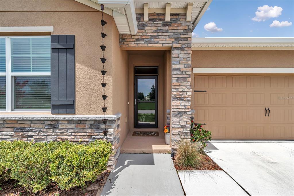 The exterior of a house features a stone-accented entryway, a garage, and a rain chain — 6365 SW 88TH LOOP, OCALA, FL
