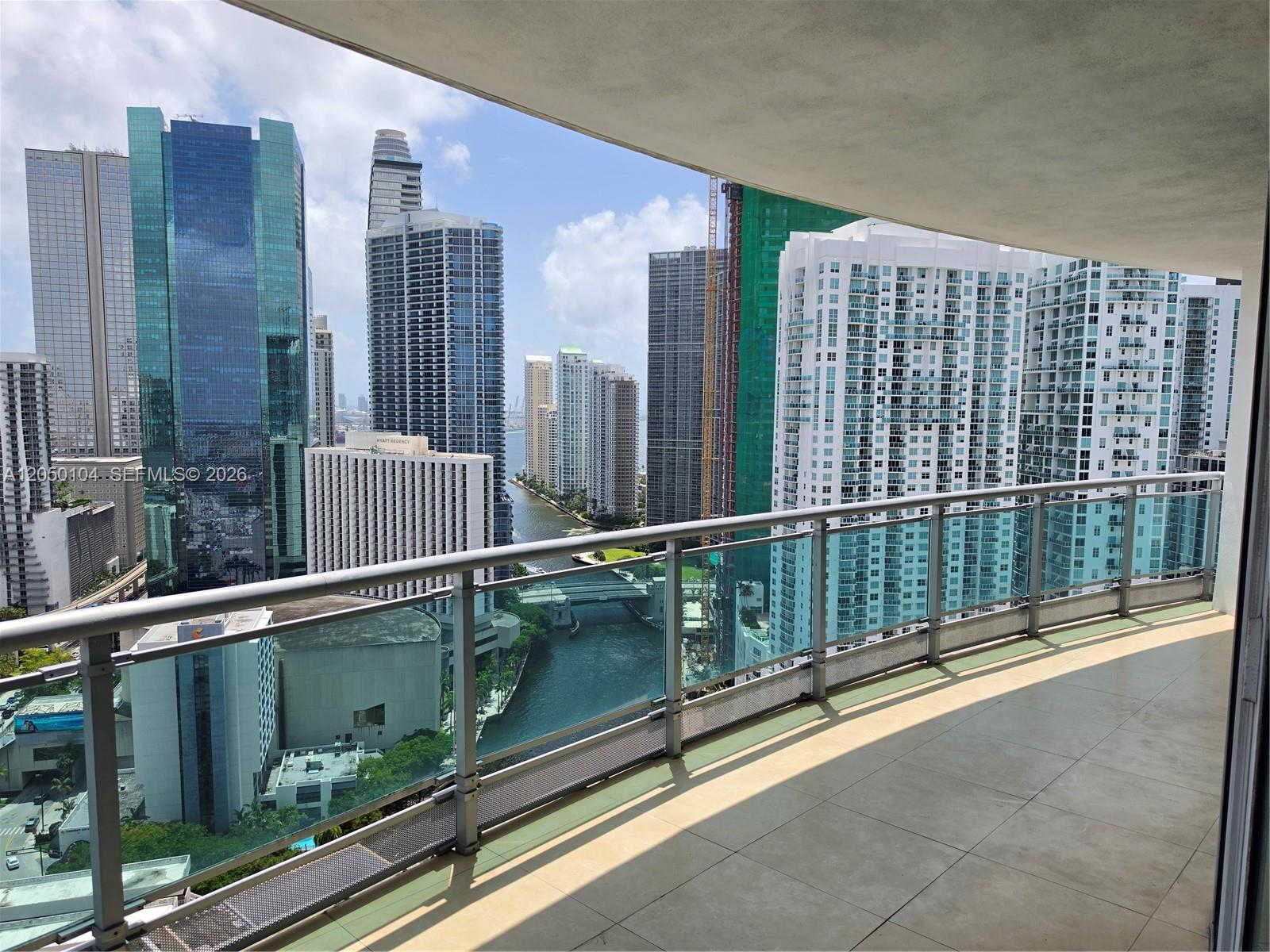 A balcony with a glass railing overlooks a city skyline and a river — 350 S Miami Ave # 3201, Miami FL 33130, MIAMI, FL