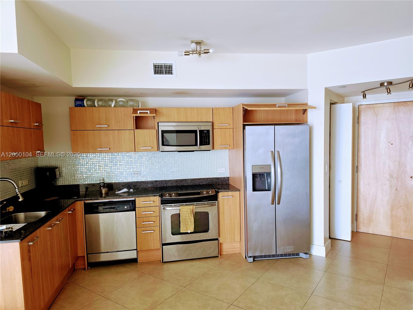 A kitchen features light wood cabinets, stainless steel appliances, and a mosaic tile backsplash — 350 S Miami Ave # 3201, Miami FL 33130, MIAMI, FL