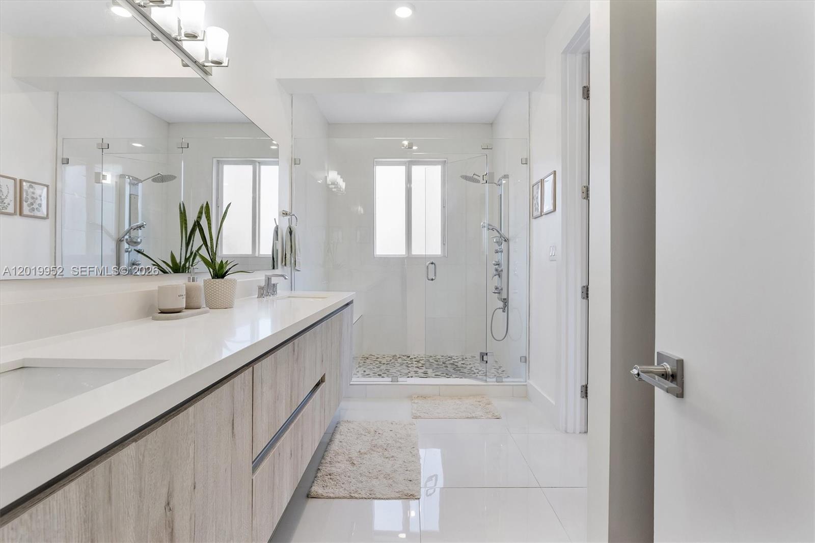 A modern bathroom features a double vanity with light wood cabinets and a glass-enclosed shower — 2920 SW 25th Ter # B, Miami FL 33133, MIAMI, FL